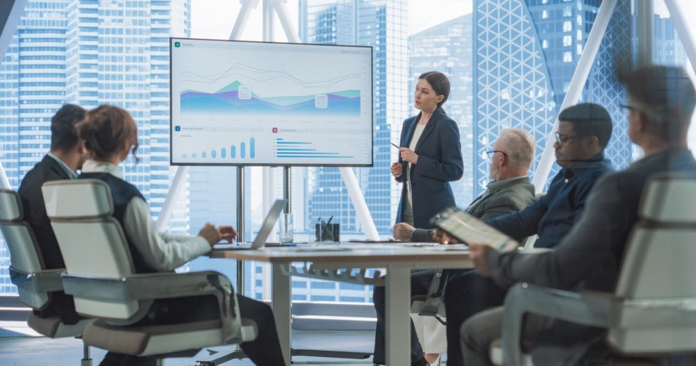 Businesswoman Talks, Uses TV Screen to Show Company Growth with Big Data Analysis