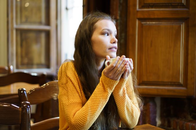 Contemplative Young Woman Enjoying Coffee in Cozy Caf