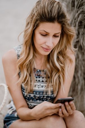female using smartphone on beach