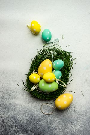 Easter festive card concept with green basket of pastel egg decorations