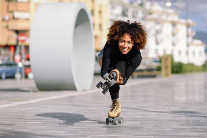 Woman with afro doing one leg tricks on roller skates