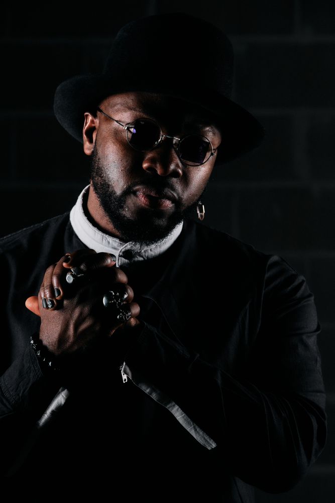 Stylish Black man in hat holding hands together