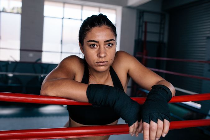 Serious female boxer inside a boxing ring with hands wrapped
