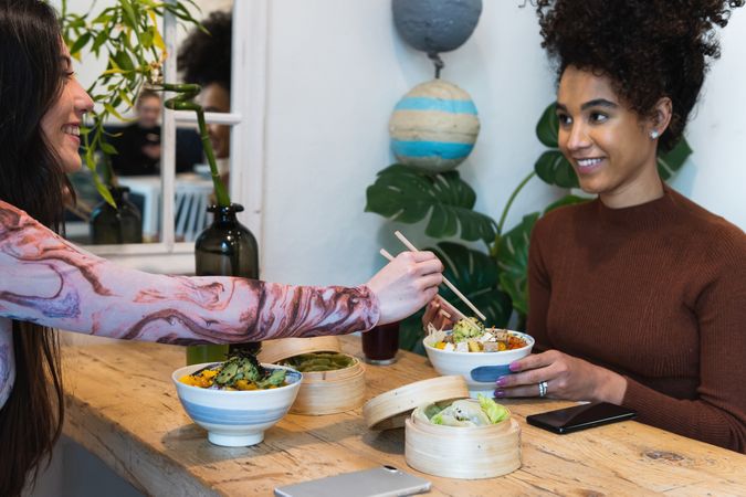 Delighted friendly multiethnic women eating in restaurant