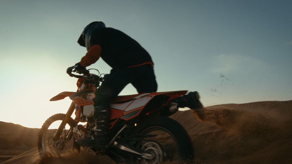 Shot of the Professional Motocross Motorcycle Rider Driving Over the Dune and Further Down the Off-Road Track.