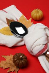 Spoon in towel, leaves and pumpkins on red background