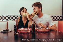 Couple at a restaurant eating burgers with soft drinks on the table 5RAL20