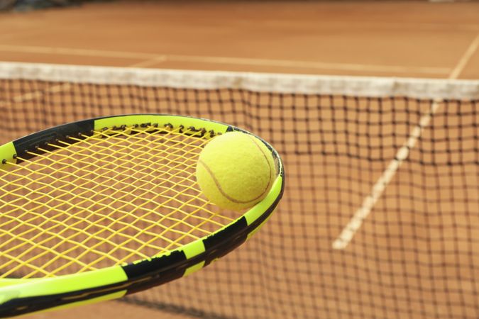 Tennis racquet with tennis ball against clay court