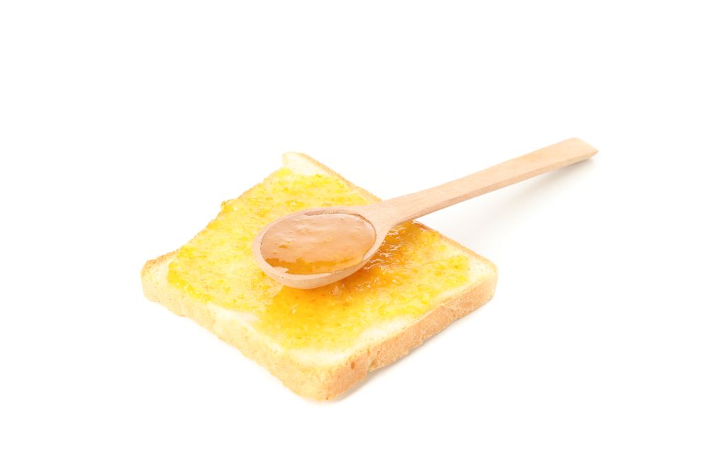 Spoon and toast with orange jam isolated on plain background