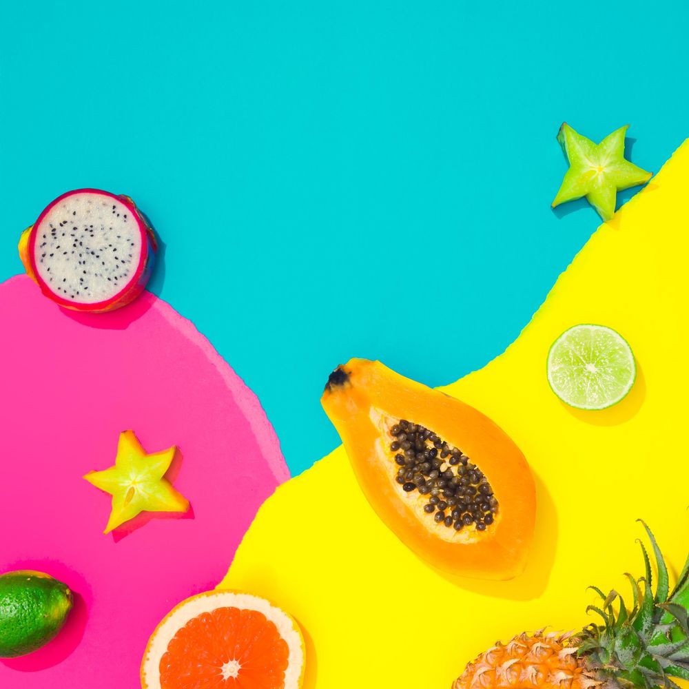 Papaya, starfruit, dragonfruit on pattern of ripped paper in vivid colors
