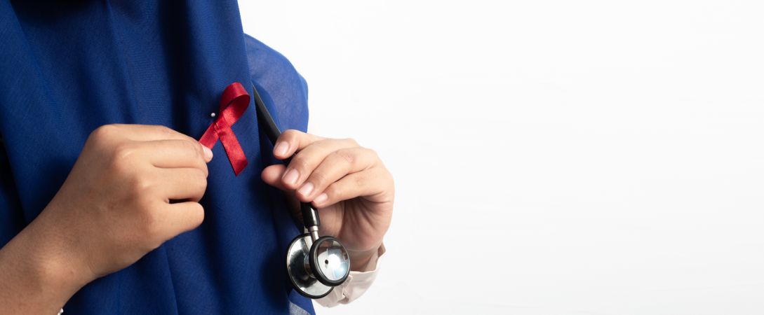 Close up Muslim Female Asian doctor or nurse wearing Red ribbons on cloth, HIV awareness concept, world AIDS day, world cancer day.