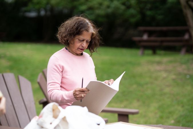 Older woman drawing in park