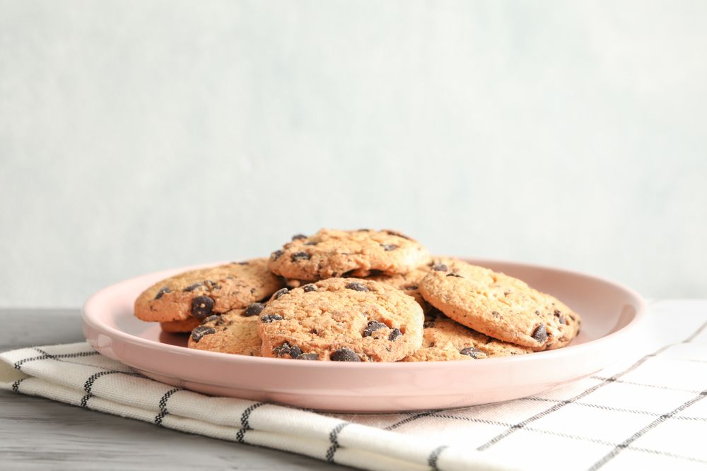 Plate with chocolate chip cookies and space for text on wooden table