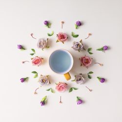 Circular flower arrangement surrounding mug on light background