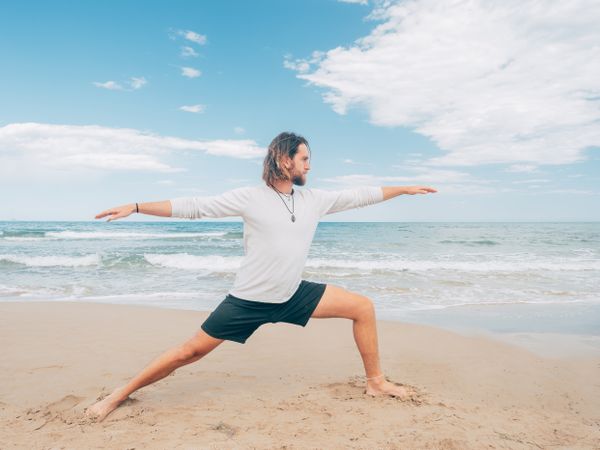 Man training yoga on beach