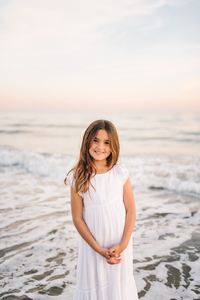 Smiling girl standing on seaside among waves