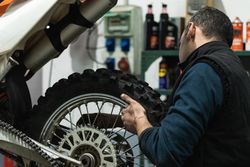 Crop mechanic changing motorbike chain in workshop