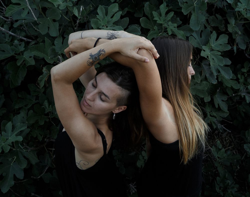 Young women posing near green bush