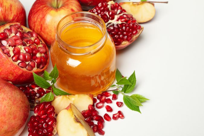 Top view of glass honey pot with pomegranate, and an apple quarters
