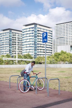 Male with colorful bicycle parking at rack in city