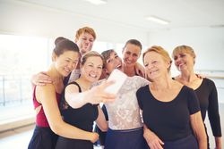Group of laughing women take selfie in bright dance studio