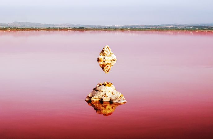 Pink lake with stones reflected in water