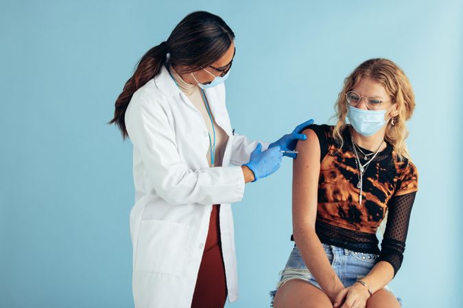 Female doctor giving vaccine to young woman