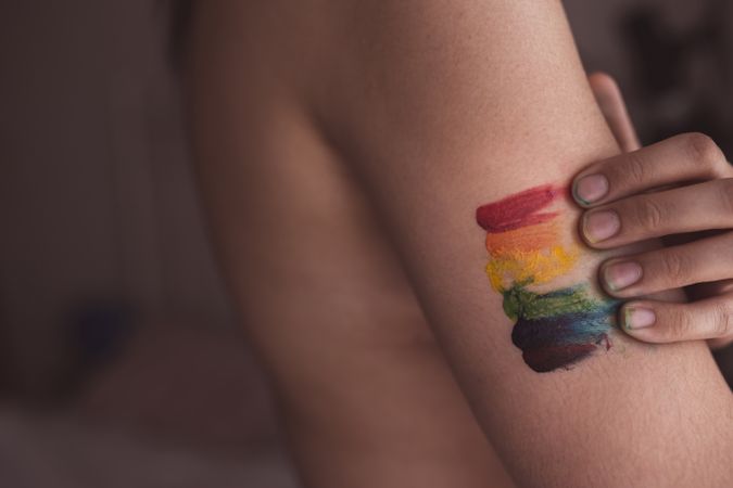 Woman covering breast with LGBTIA symbol