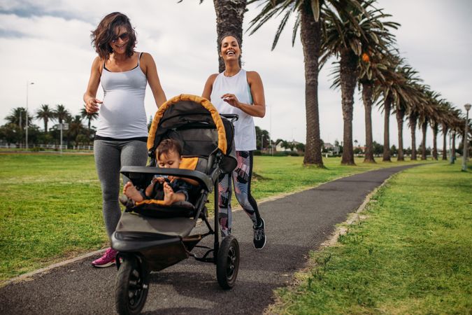 Two women walking with a baby pram in a park