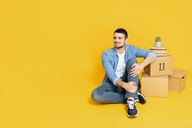 A man with boxes, on a yellow background, the concept of moving.