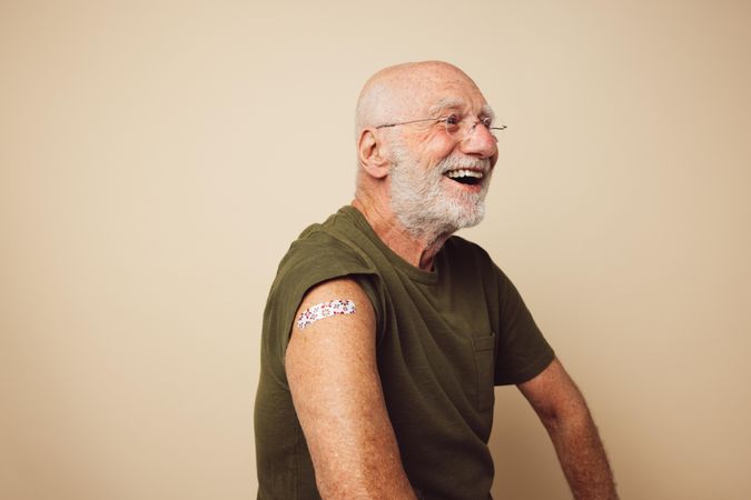Portrait of mature man with bandage on arm after getting vaccine