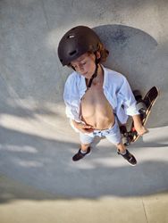 Young boy wearing helmet lying on asphalt