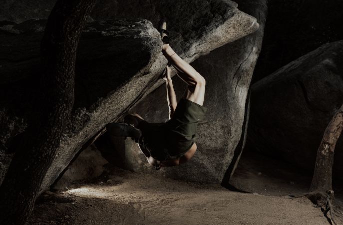 Man practicing rock climbing among large rocks in a forest