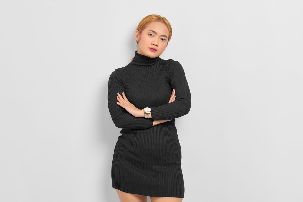 Asian woman with red hair modeling with arms crossed in studio
