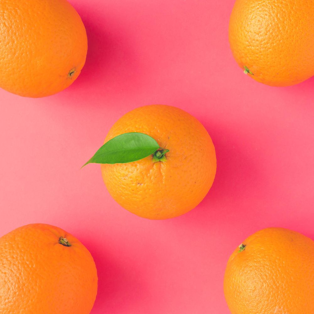 Whole oranges on vivid pink background