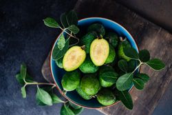 Top view of blue bowl of organic fruit feijoa