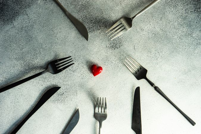Cutlery on grey counter with red heart in the center 