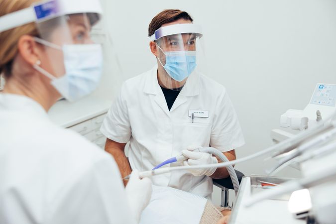 Dentists treating a patient with dental equipment