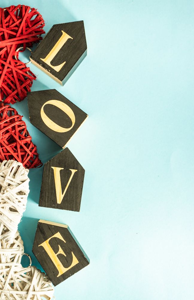 Word "love" on blue pastel table with thatched hearts