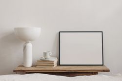 Cup of coffee, books and modern marble geometric lamp on vintage teak wooden bench next to mock up poster frame