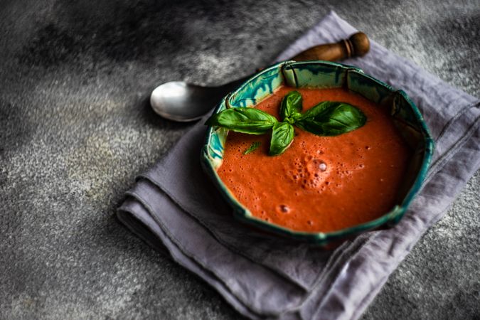Traditional Spanish tomato soup Gazpacho with basil on grey counter