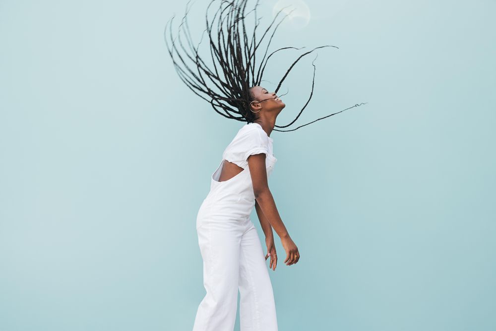 Smiling Black woman with long braids shaking her hair