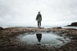 Female standing on cliff and contemplating