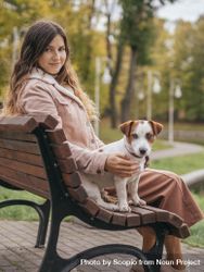 Woman sitting beside dog on wooden bench 0gQ9M4