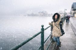 Woman on lakeshore smiling while standing outside in the snow by a lake