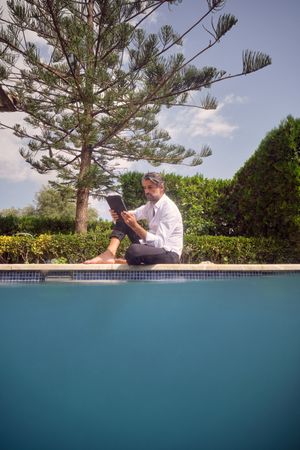 Man browsing tablet at poolside