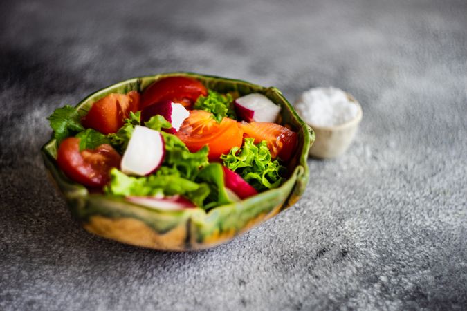 Vegetable salad with tomatoes, radish & lettuce on concrete background with copy space