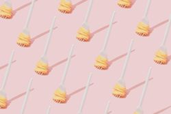Rows of plastic fork with pasta pattern against pastel pink background
