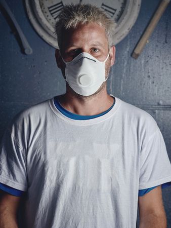 Blond surfboard maker with tattoos in mask