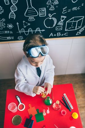 Boy playing with chemical liquids over red table